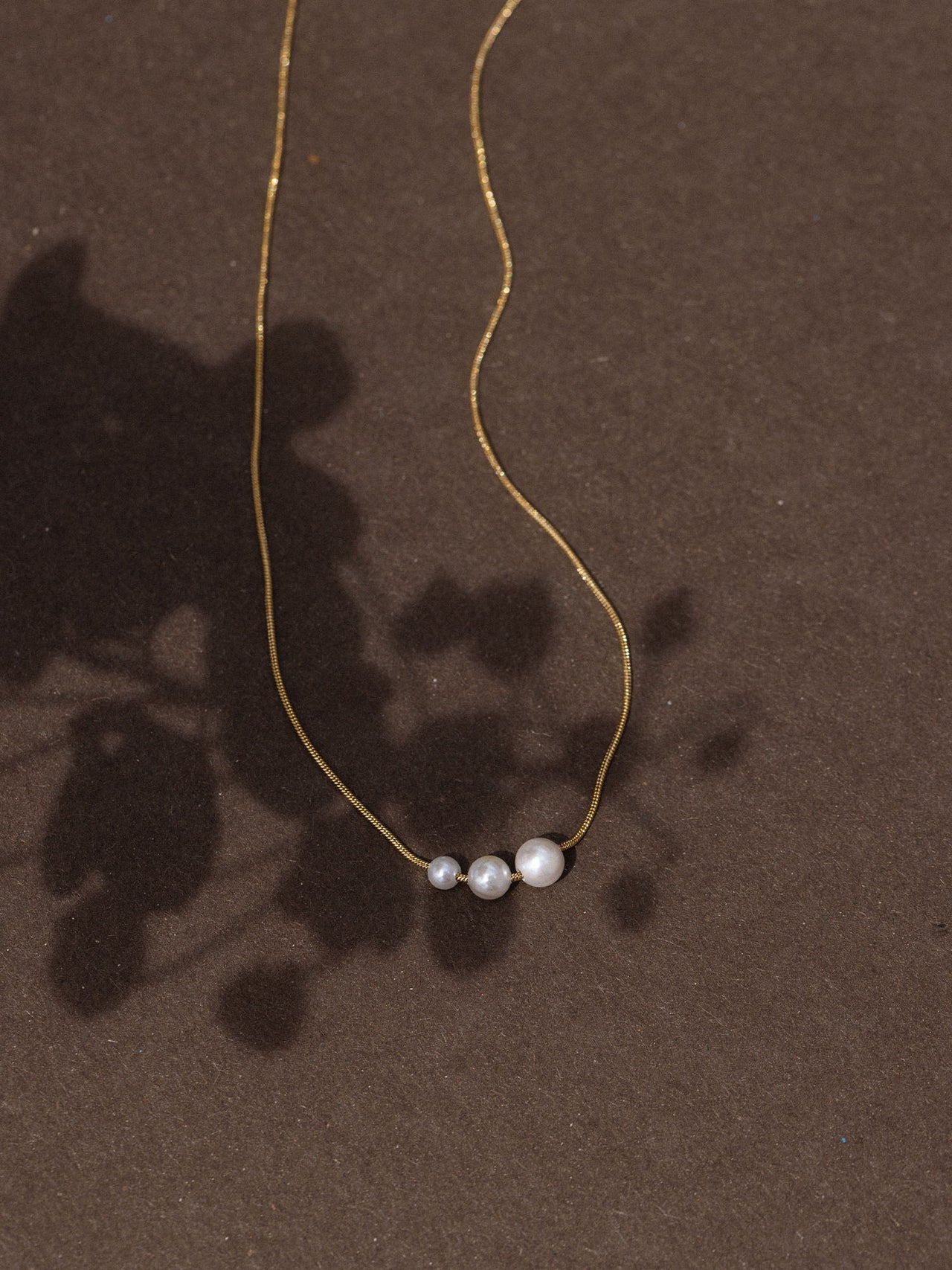 Schlichte PURELEI Kette mit drei runden Anhängern auf dunklem Hintergrund, elegant und modern.