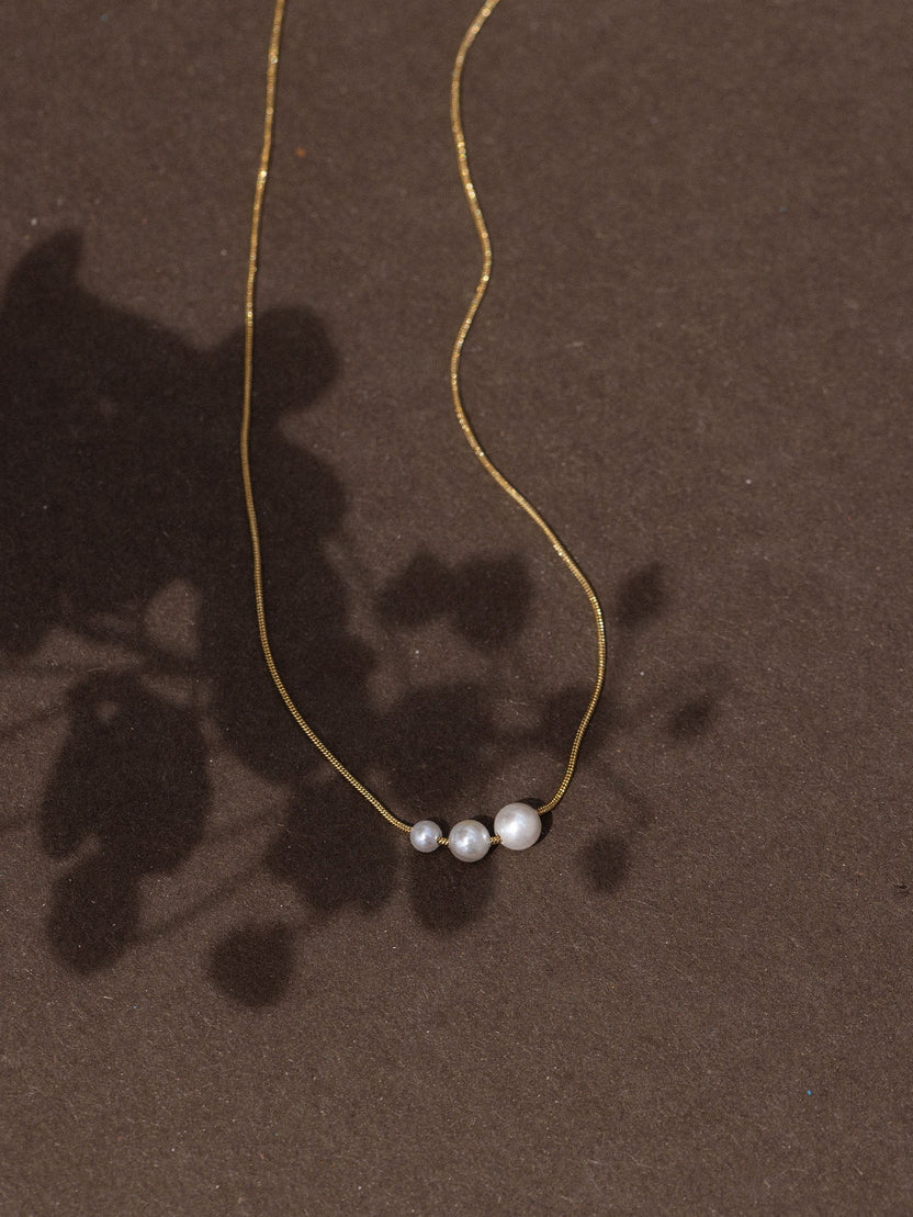 Schlichte PURELEI Kette mit drei runden Anhängern auf dunklem Hintergrund, elegant und modern.