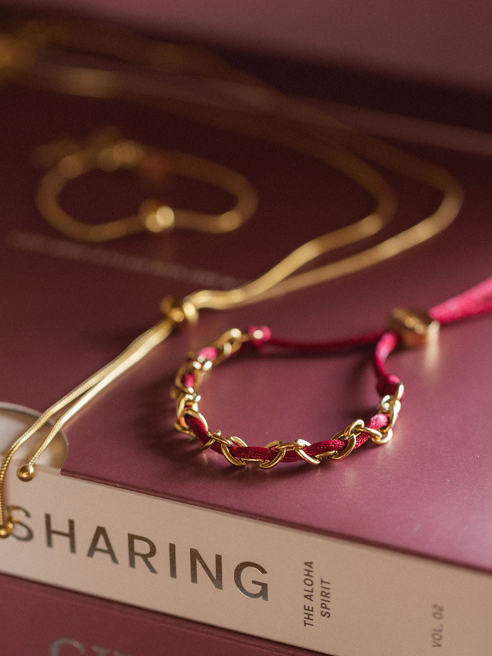 PURLEI Armband aus silbernem Metall und lila geflochtenem Band, elegant auf Buch präsentiert. PURELEI