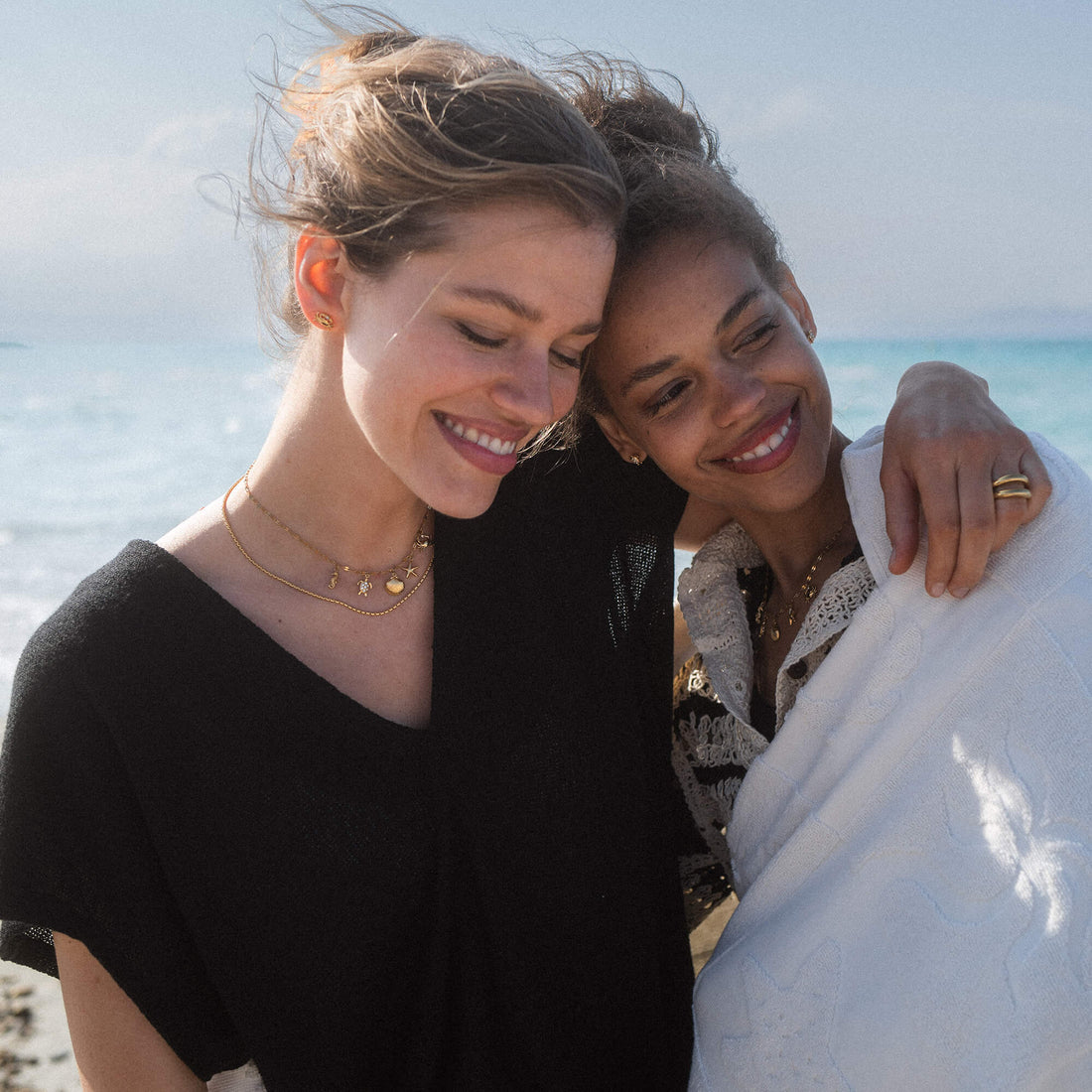 Zwei Frauen am Strand, eine trägt PURELEI Kette mit Sternen, entspannte, sonnige Stimmung.