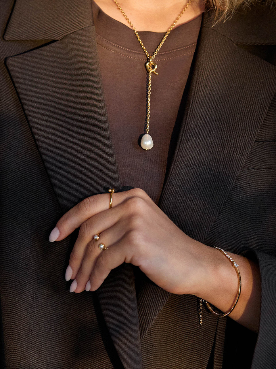 Elegante goldene Kette mit Anhänger und Ringen, getragen in einem stilvollen Outfit von PURELEI.