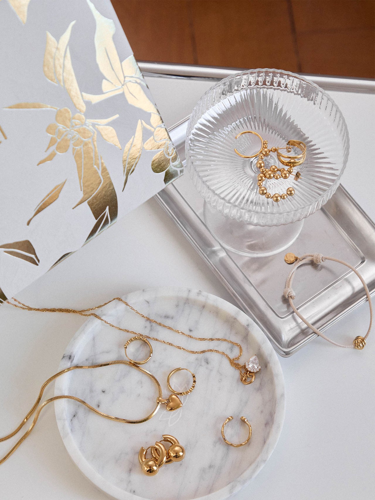 Goldene Schmuckstücke von PURELEI auf marmoriertem Teller, elegant und feminin.