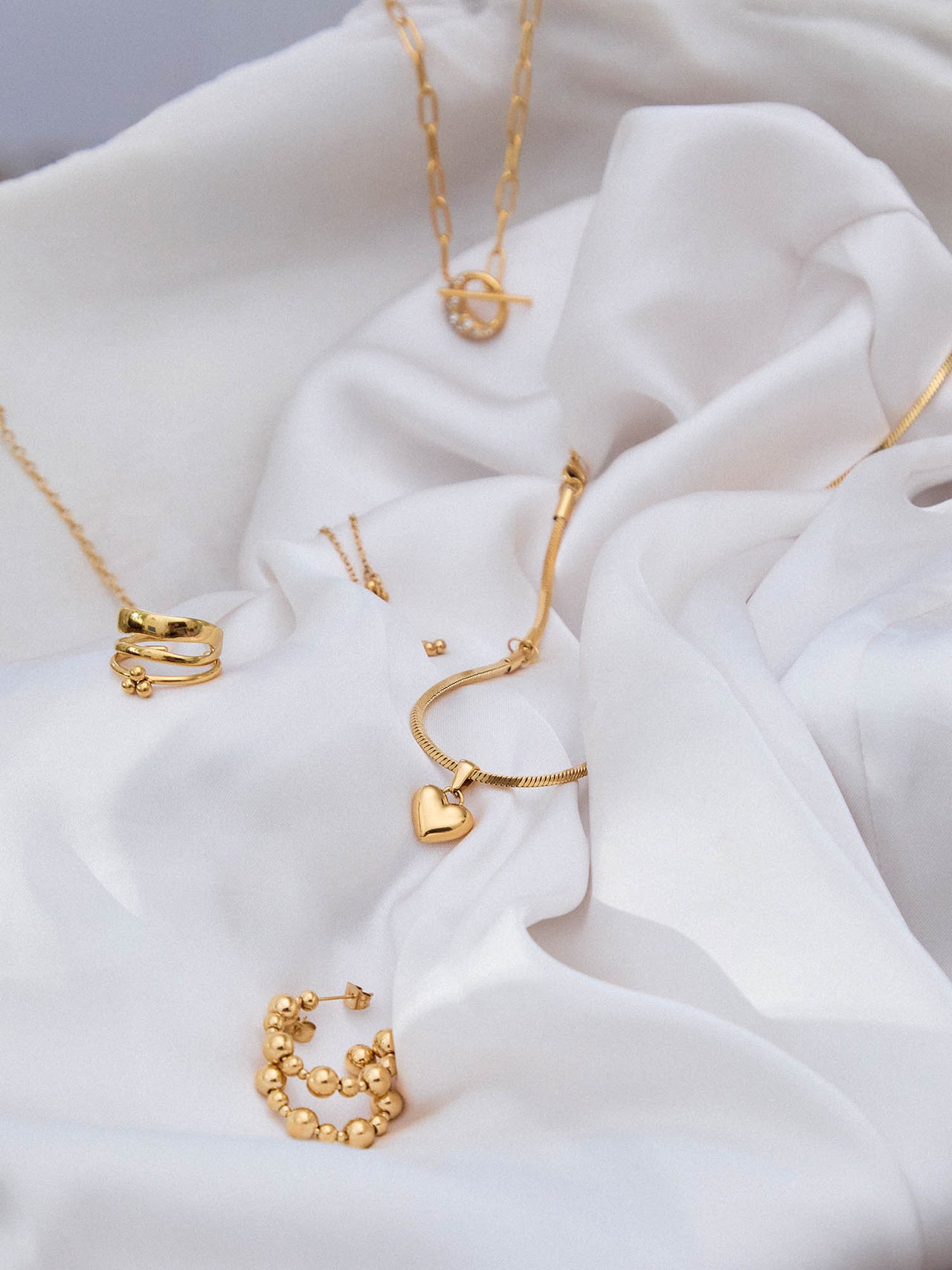 PURELEI Adventskalender 2024, goldene, nickelfreie Schmuckstücke auf elegantem, weißem Stoff, feminine Leichtigkeit