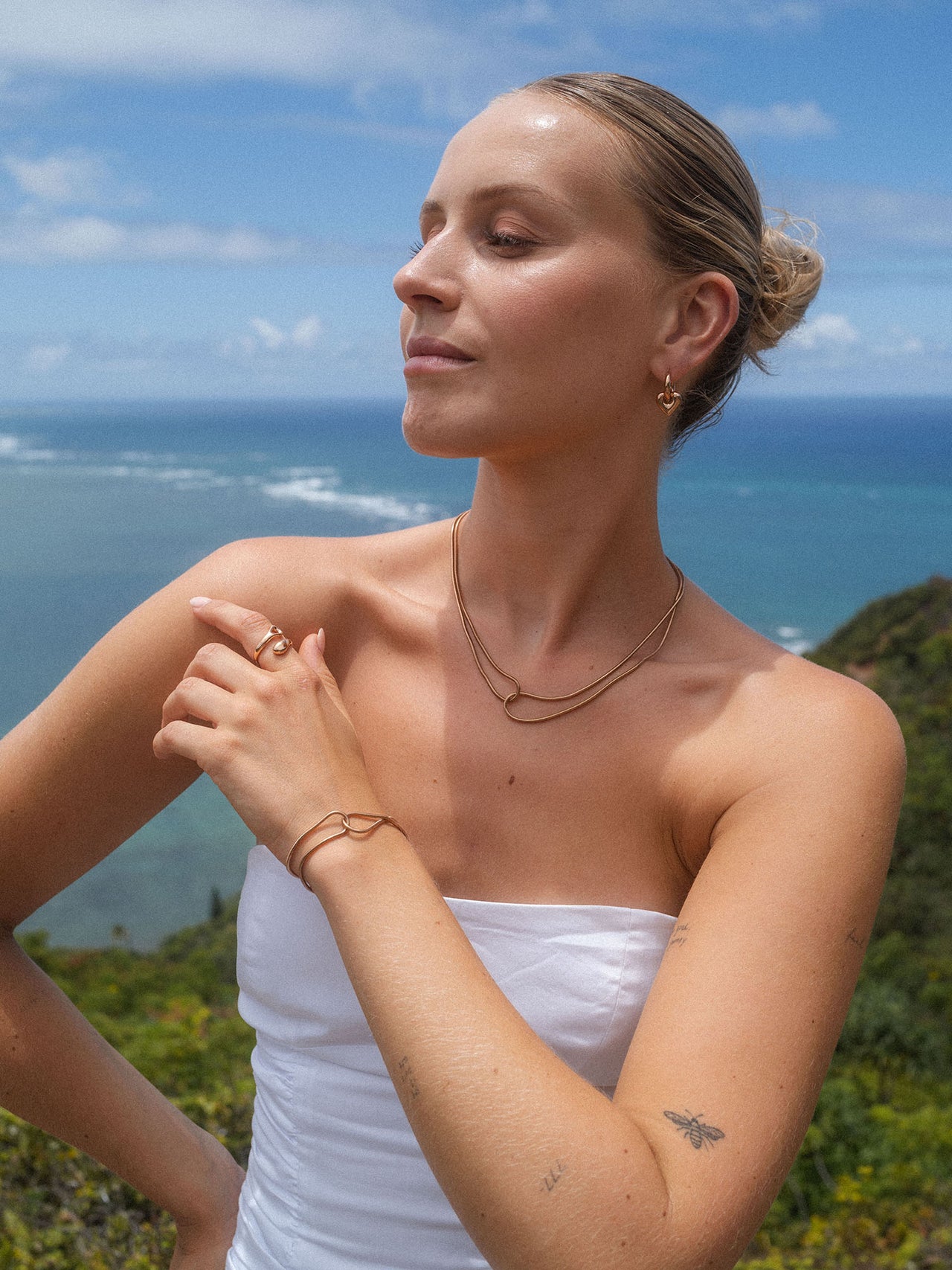 Zarte, roségoldene Kette und Armband von PURELEI, umgeben von tropischer Kulisse.