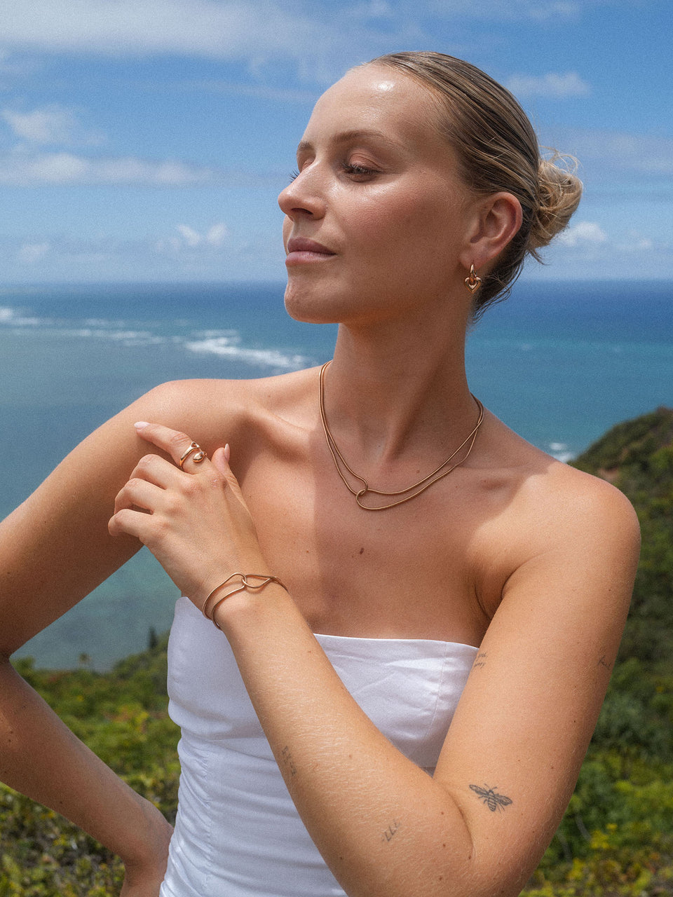 Zarte, roségoldene Kette und Armband von PURELEI, umgeben von tropischer Kulisse.