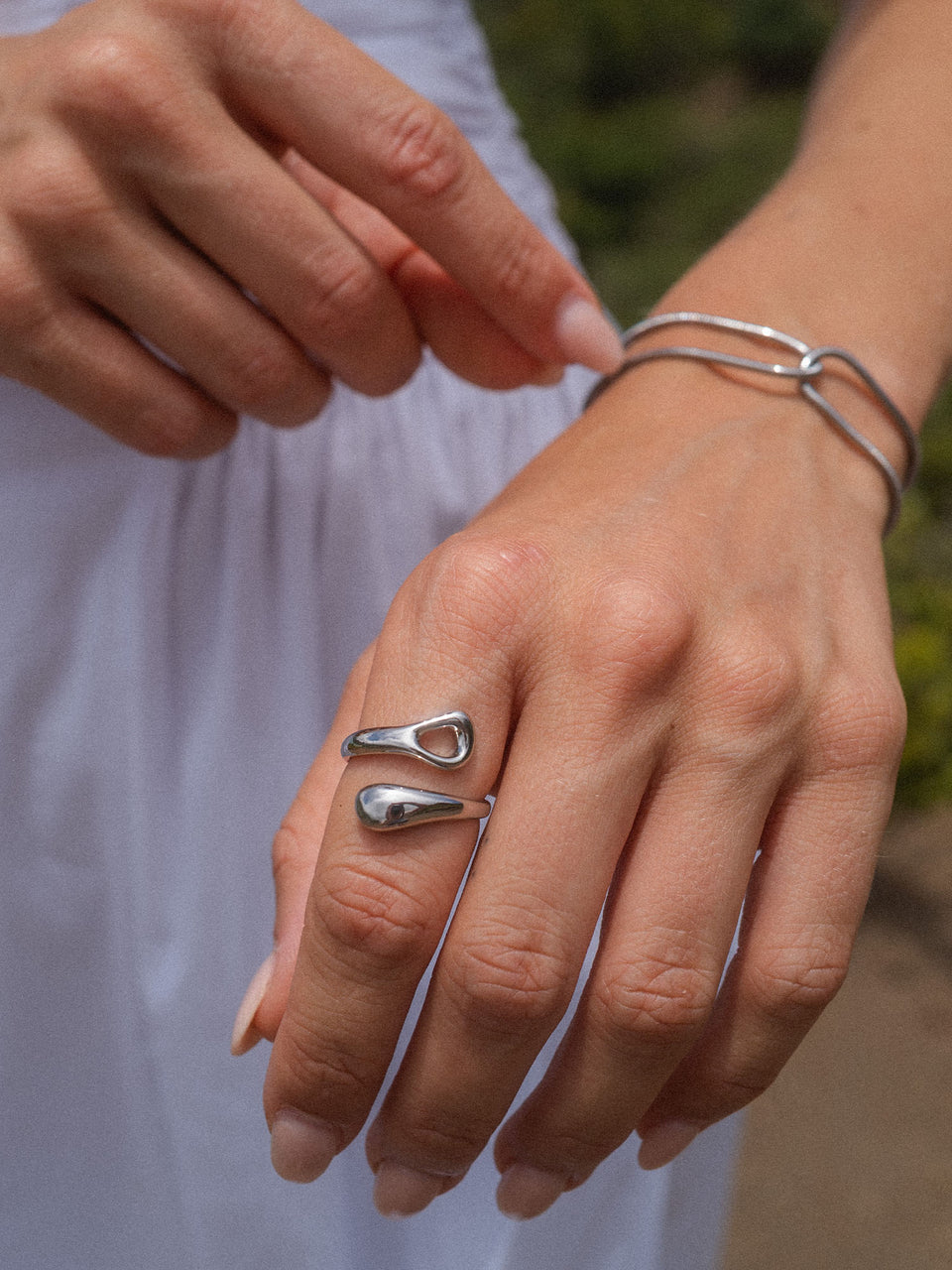 Silberner Ring mit fließendem Design, getragen an einer Hand, PURELEI inspiriert.
