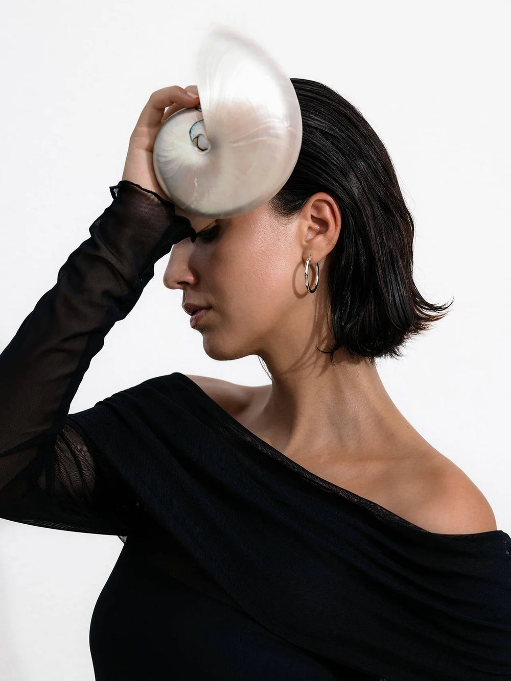 Elegante Muschel auf schwarzem Top, getragen von einer Frau, PURELEI inspiriert.