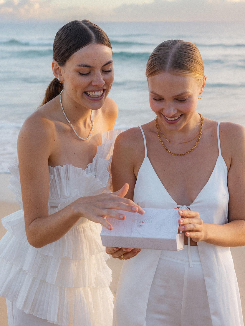 Geschenkbox S von PURELEI in Beige mit dezentem Pflanzenmuster, Magnetverschluss und edlem Logoschriftzug am Strand.