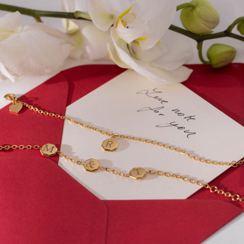 Gravur-Service - Eternal Kette in Gold mit individuellen Buchstaben, elegant inszeniert mit weißer Orchidee und rotem Briefumschlag von PURELEI