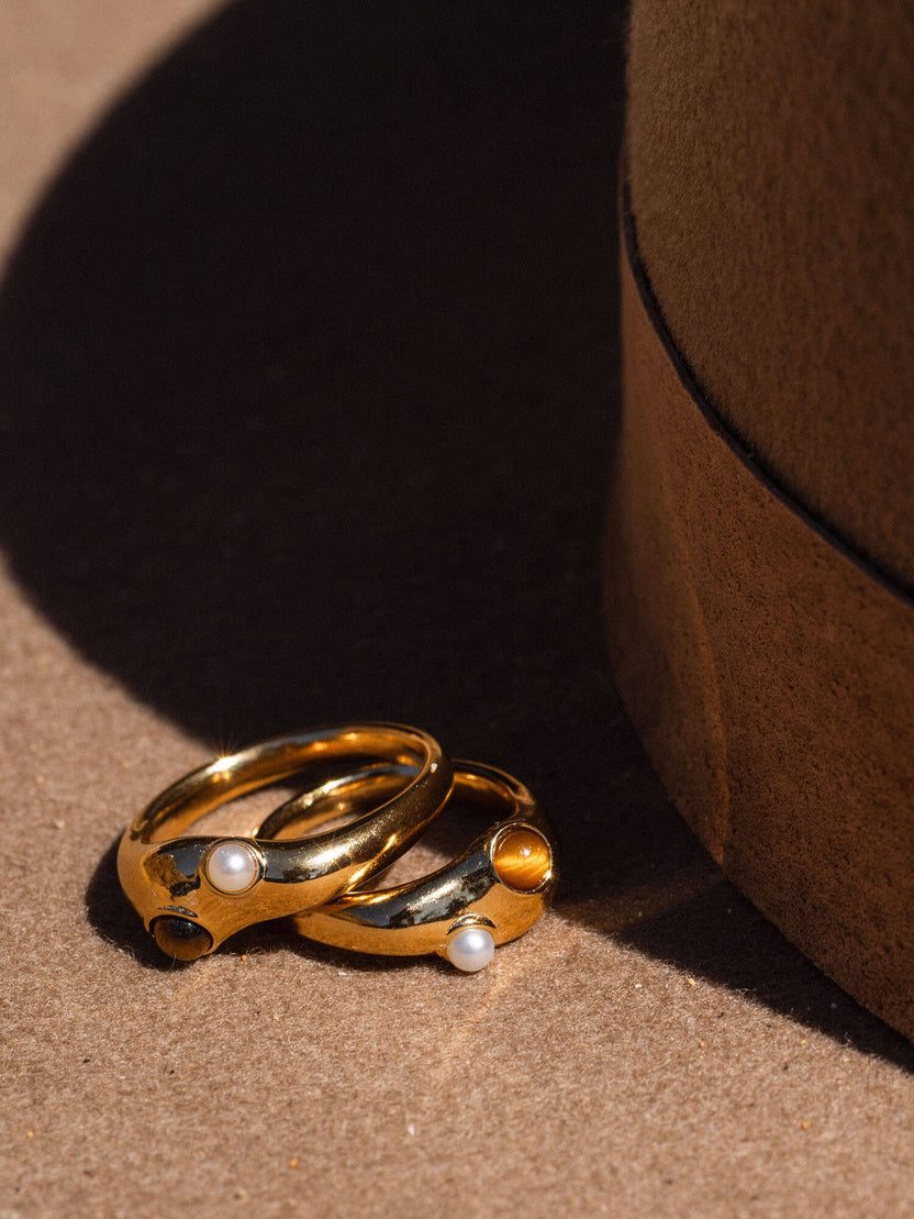 Goldene Ringe mit weißen und schwarzen Steinen, PURELEI, elegant und modern.