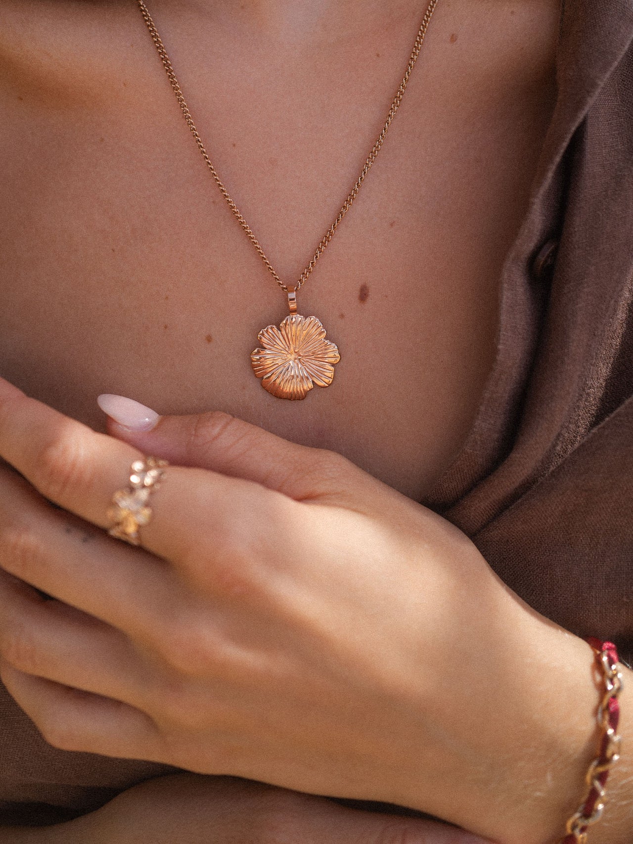 Roségoldene Blütenkette von PURELEI, elegant und feminin, getragen auf sanftem Stoff.