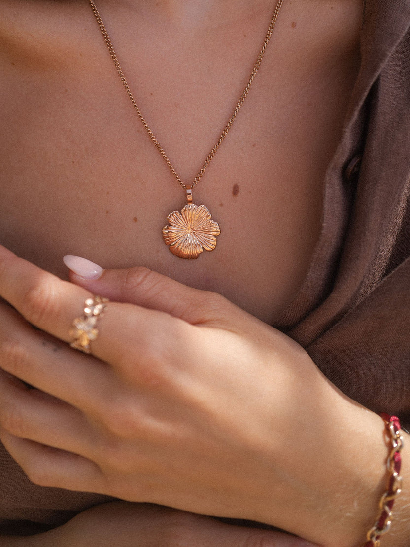 Roségoldene Blütenkette von PURELEI, elegant und feminin, getragen auf sanftem Stoff.