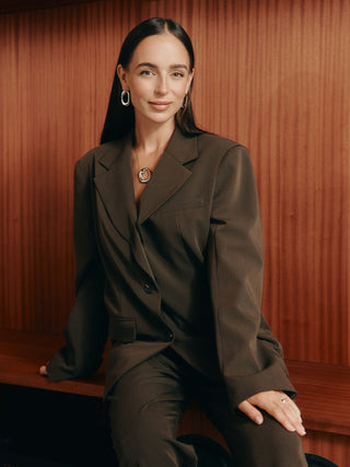 Elegante PURELEI Kette mit Anhänger, getragen in einem stilvollen Outfit, warmes Licht im Hintergrund.