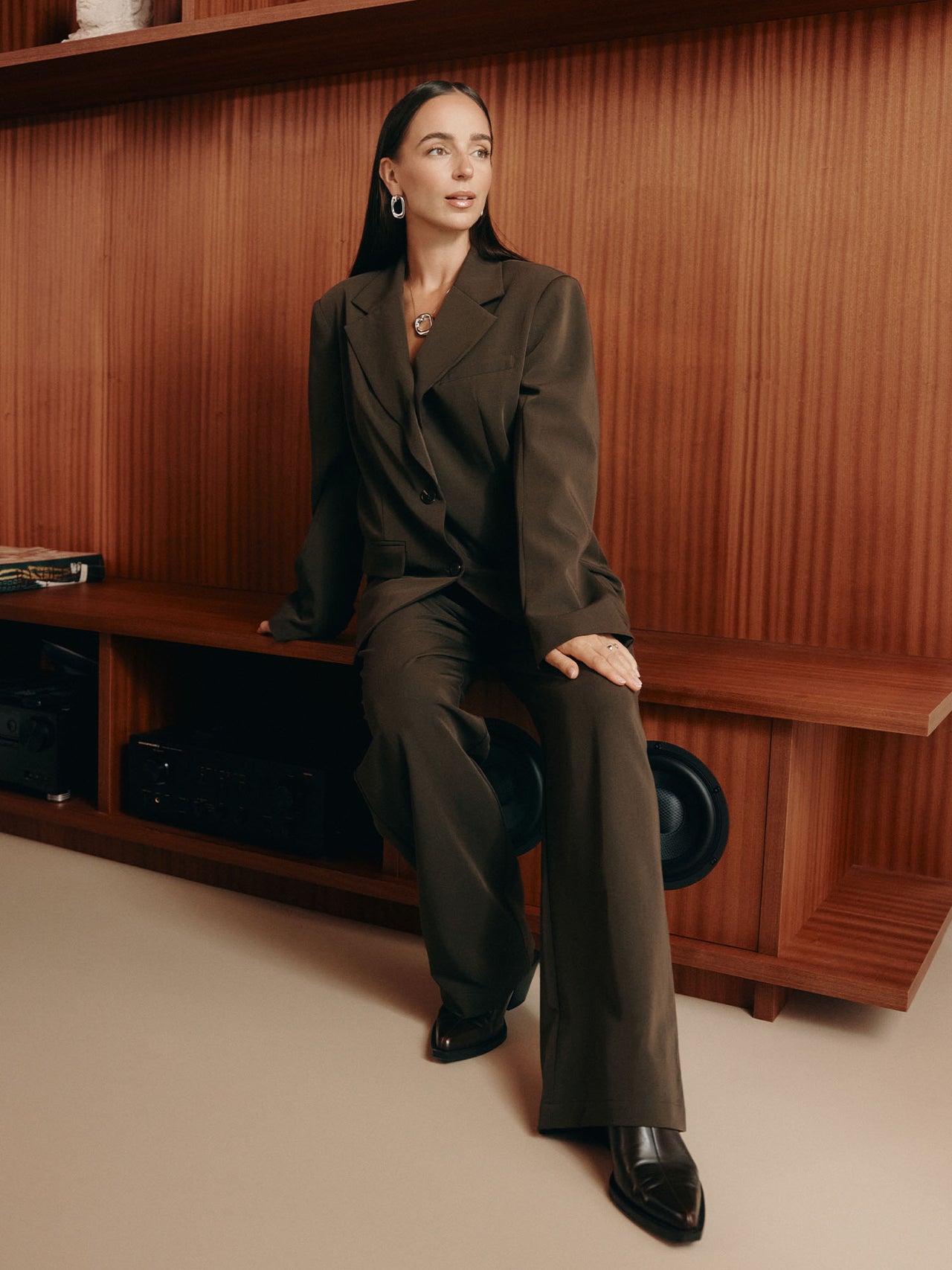 Elegante, schwarze PURELEI Kette mit Anhänger, getragen in stilvollem Outfit vor Holzregal.