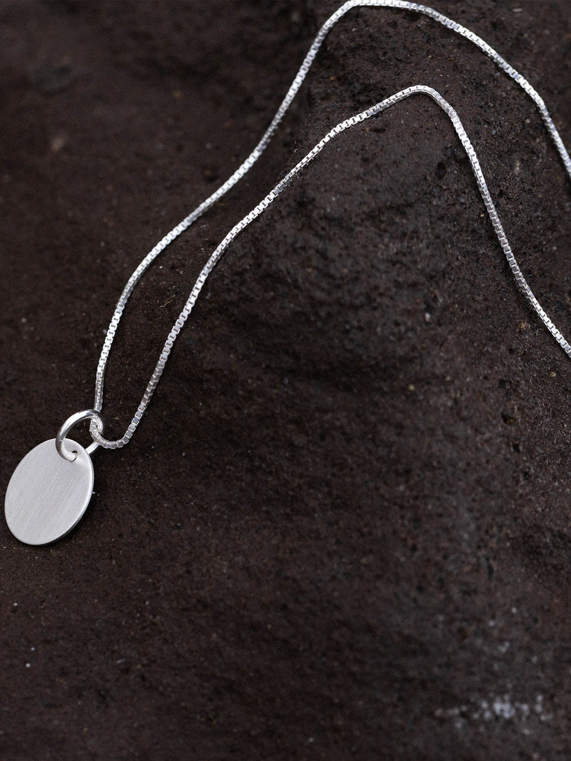 PURELEI Perfection Kette aus recyceltem Silber mit gravierbarem Charm auf dunklem Lavastein, zeitlos elegant.
