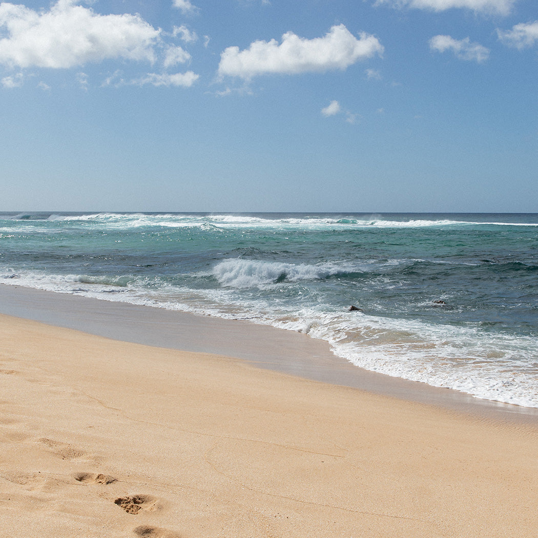Strand mit sanften Wellen und hellem Sand, inspiriert von PURELEI's Aloha-Feeling.