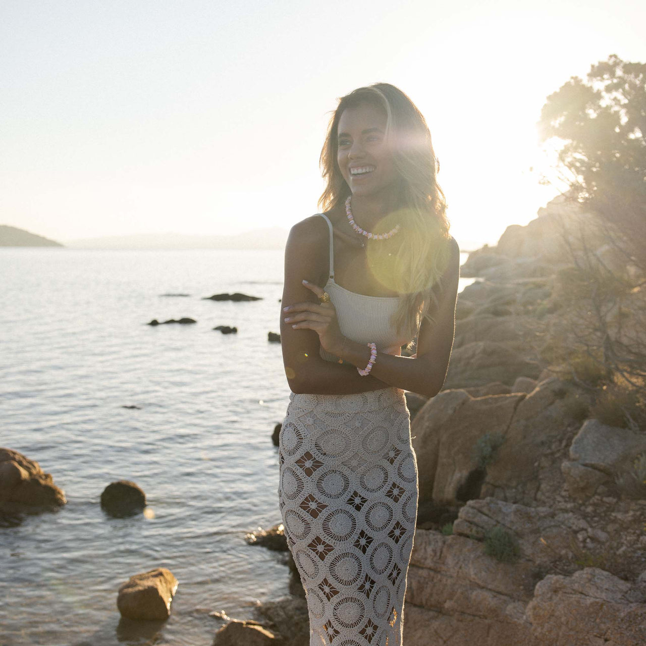 Summer Fußkette von PURELEI mit goldenen Anhängern und Perlen am Strand, elegant und feminine Urlaubsstimmung.