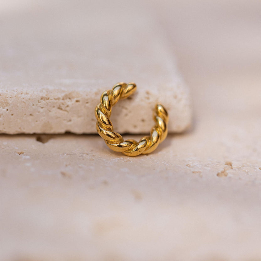 Goldene, gewundene Creole auf hellem Stein, inspiriert von PURELEI.