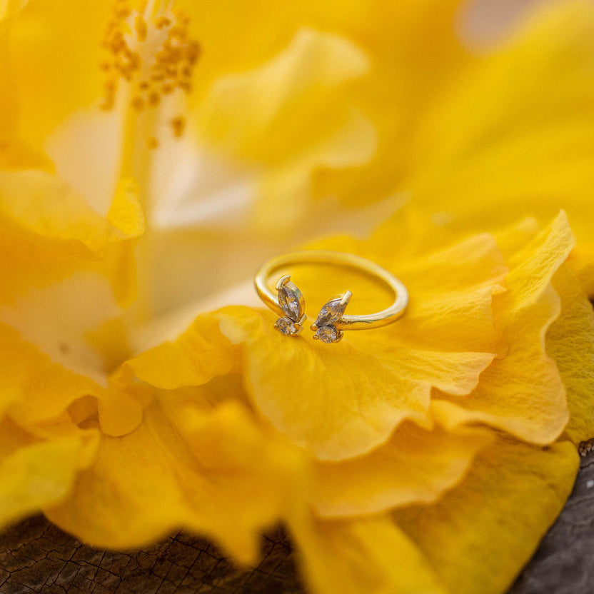 Goldener Ring mit Blattdesign auf gelber Blüte, inspiriert von PURELEI.